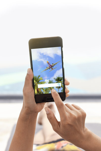 一个女人在泳池边放松的照片。她的手正在触摸手机屏幕，探索新的旅行。图片下载