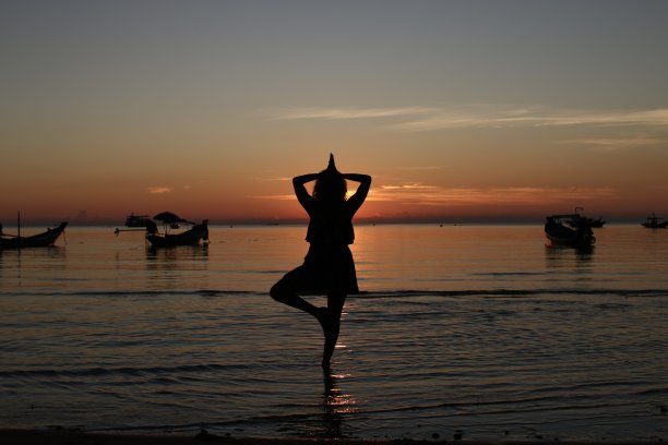 海滩上夕阳下的瑜伽女子图片下载