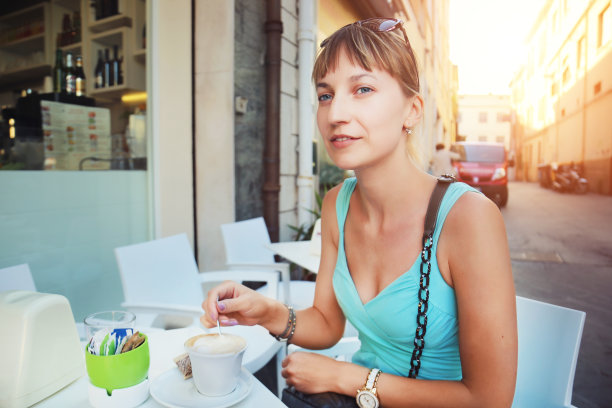 年轻美丽的女人在意大利街头的咖啡馆，享受在罗马喝咖啡。在欧洲度假期间，一个漂亮的女孩正在吃早餐。坦诚的人生活方式旅行场景图片下载