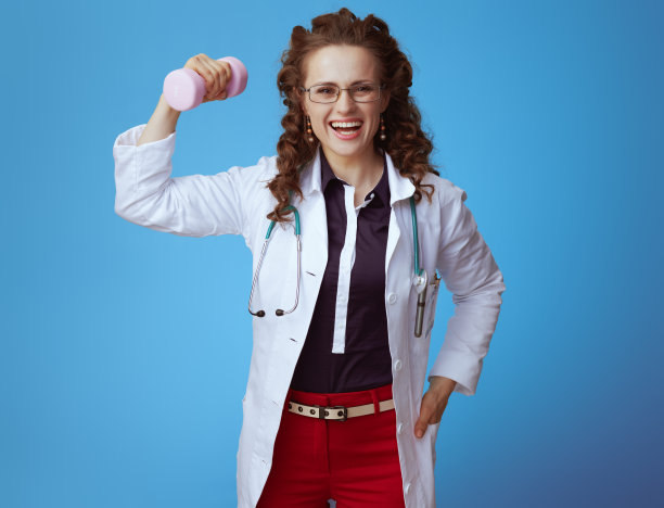 微笑的女医生与粉红色哑铃显示二头肌在蓝色图片下载