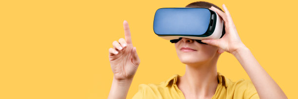 30多岁的年轻女子戴着虚拟现实眼镜。戴着虚拟现实头盔的女子被隔离在黄色横幅上。虚拟现实体验的概念。图片下载