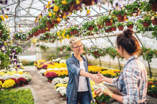 愉快的白人花商在围裙拿着药片和握手与快乐的顾客。图片下载