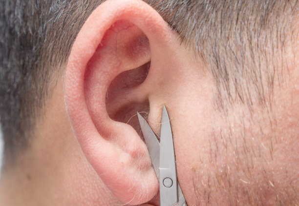 男人用小剪刀剪掉耳朵里的头发。特写,有选择性的重点。图片下载