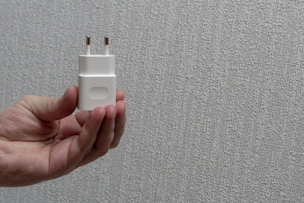 一只手拿着一个白色的充电器适配器。图片下载