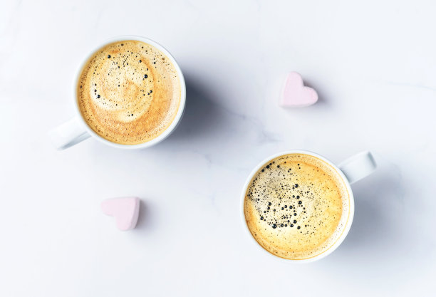 浪漫的桌面有两杯咖啡和粉红色的心形棉花糖。前视图。图片下载