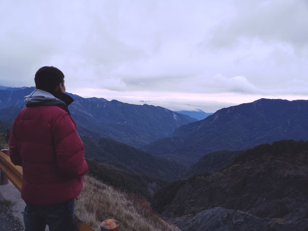 年轻的亚洲男子享受风和雾在山顶与美丽的风景在背景图片下载