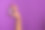 女人的手拿着白色的化妆品瓶在紫罗兰的背景。横幅。护肤，纯美，身体护理理念图片下载