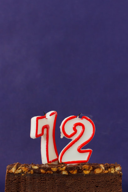 生日快乐的布朗尼蛋糕花生，咸焦糖和彩色的蜡烛在紫罗兰背景。复制空间的文本。72号。图片下载