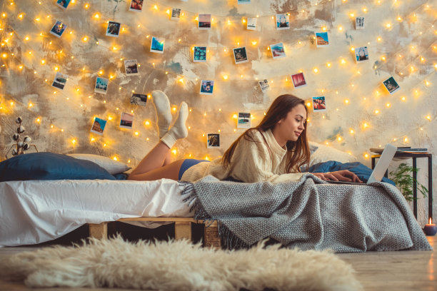 年轻女子周末在家用笔记本电脑装饰卧室图片下载