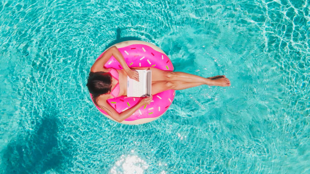 年轻女子在海里游成一个游泳圈。女孩在游泳池里用电脑围成一个充气圈，俯视图图片下载