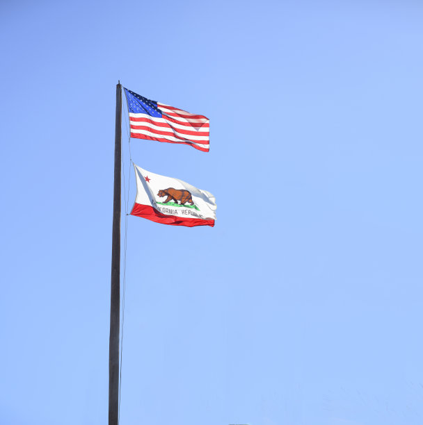 湛蓝的天空，旗杆上挂着加州和美国国旗图片下载