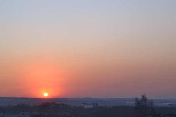 冬天结束时城市上空的红色日落。景观。太阳在一层红色的薄雾中下沉到地平线上。图片下载