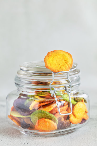 五彩缤纷的蔬菜片放在玻璃罐中，垂直组成图片下载