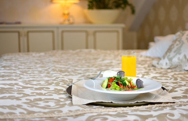 在酒店房间的床上睡觉后，用新鲜有机蔬菜沙拉和橙汁来提神。图片下载