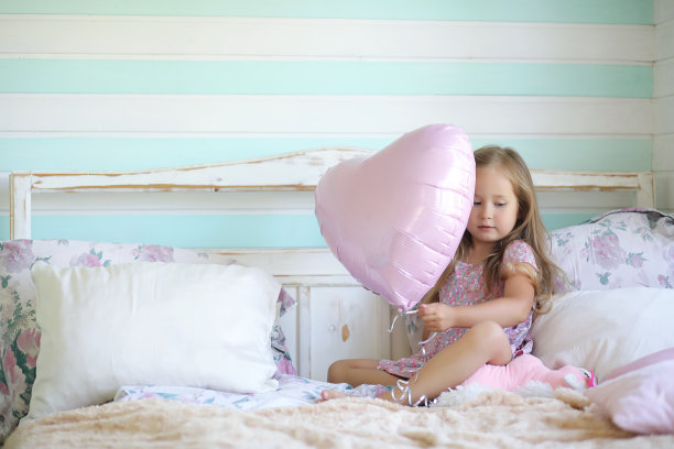 一个小女孩带着一个女儿坐在床上。避暑别墅在花园旁边的村子里。剩下的是一个年轻的母亲和女儿在村子里。图片下载