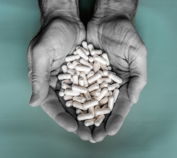 男人的手握维他命或处方药。保健或成瘾概念。图片下载