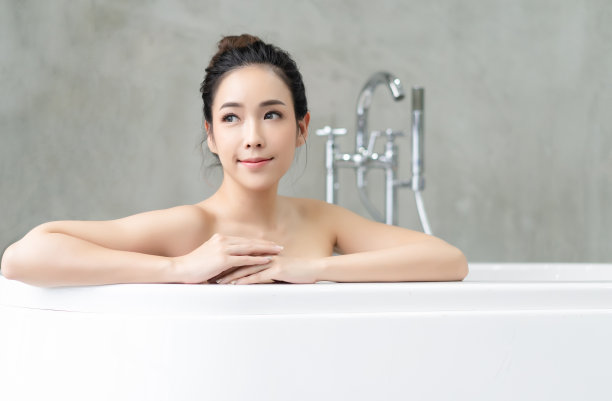 近距离肖像迷人的亚洲女士放松和看别处，而坐在浴缸里。水疗美容和健康与皮肤护理。图片下载