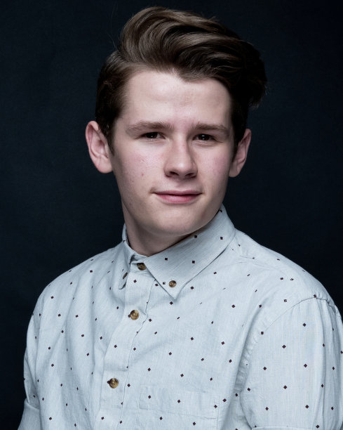 年轻英俊的男子站在黑色背景前图片下载