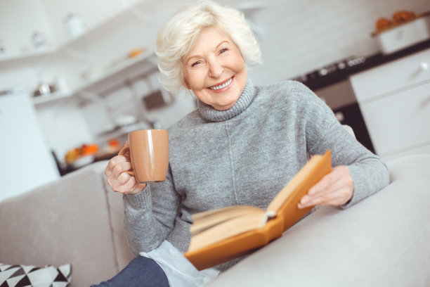 快乐的老妇人一边看书一边喝咖啡图片下载