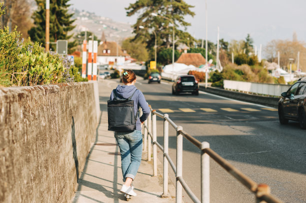 年轻的女孩骑摩托车旁边的路，背着背包，后视镜图片下载
