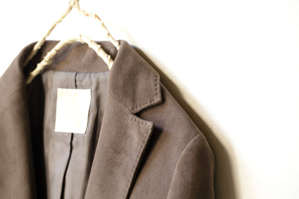 深棕色夹克挂在衣架上，白色背景。图片下载