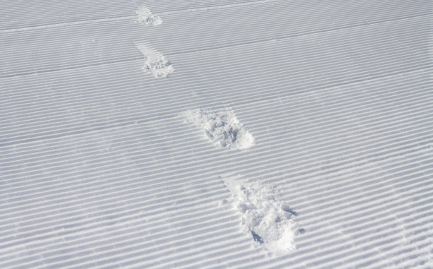 雪车的痕迹和脚印在冬季的山丘和积雪覆盖的景观图片下载