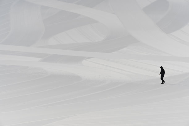 一个男人走在白色的滑雪坡道上。图片下载