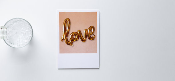 一杯苏打水和一个写着爱的信息的宝丽来。白色的桌子从上面。带有文本空间的横幅模型概念。图片下载