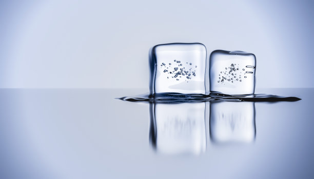 两个融化的冰块，泡沫反射在光滑的表面上图片下载