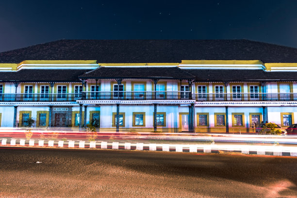 印度盘吉姆果阿政府的老秘书处大楼，在深夜，快速运行的交通灯的轨迹和天空中的星星。入口的印地语文字意味着只有真理才能胜利。图片下载