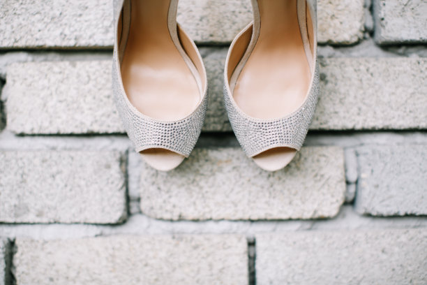银色的高跟鞋挂在砖墙上图片下载
