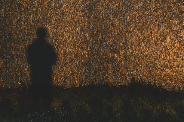 夕阳下一个人的剪影投射在建筑围板上图片下载