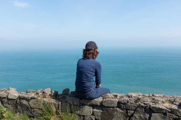 女士在晴朗的一天里背对镜头看着大海图片下载
