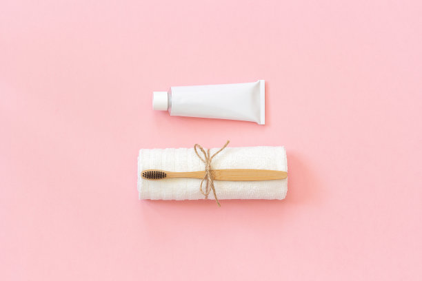 天然环保竹刷白毛巾和牙膏管。设置为在纸上粉红色的背景上洗涤。复制空间的文本或您的设计俯视图平铺图片下载