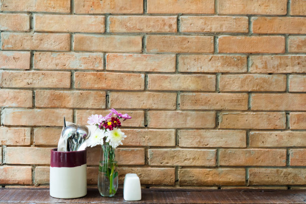 桌上的砖墙上放着鲜花、器皿和调味品图片下载