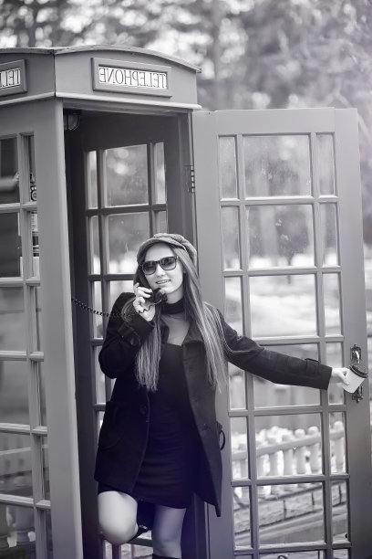 电话亭里的漂亮姑娘。那个女孩正在公用电话亭里讲电话。街上的英语电话亭和一个正在打电话的女人。图片下载