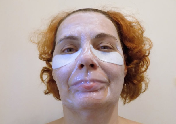 女士与再生化妆品面膜在她的脸上，并补丁对抗皱纹周围的嘴和眼睛图片下载
