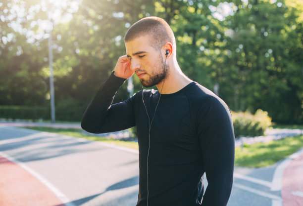 年轻的跑步者用智能手机听音乐。图片下载