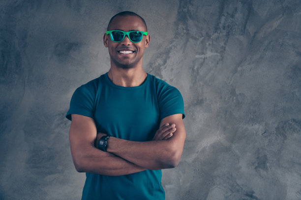 近距离的照片惊人的惊人的他他，他的黑皮肤，男子气概，热辣的现代的样子，趋势手，手臂，折叠的假期，伟大的一天，心情，天气，兴奋，穿眼镜，休闲的蓝色t恤孤立的灰色背景图片下载