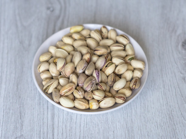 健康的食物背景图片近距离开心果。纹理上的白色灰色表顶视图。果仁，开心果，放在盘子里图片下载