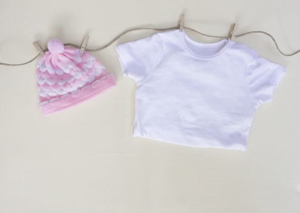 粉织帽和白衬衫挂在布衣架上，底色为淡黄色图片下载