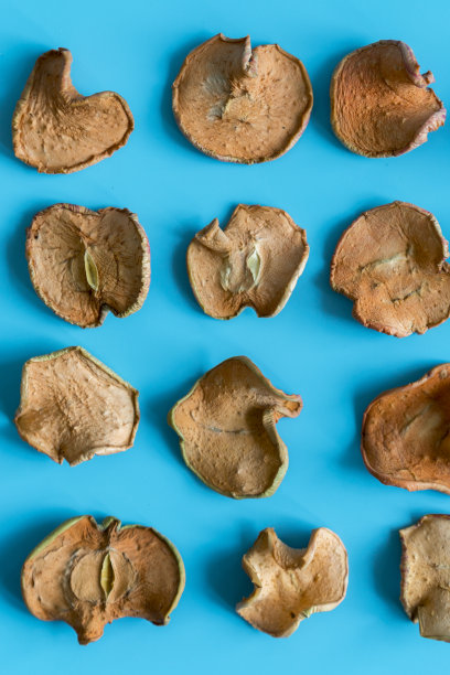 蓝色背景上的干苹果片。景深浅。自制晒干的有机苹果片。垂直的照片。图片下载