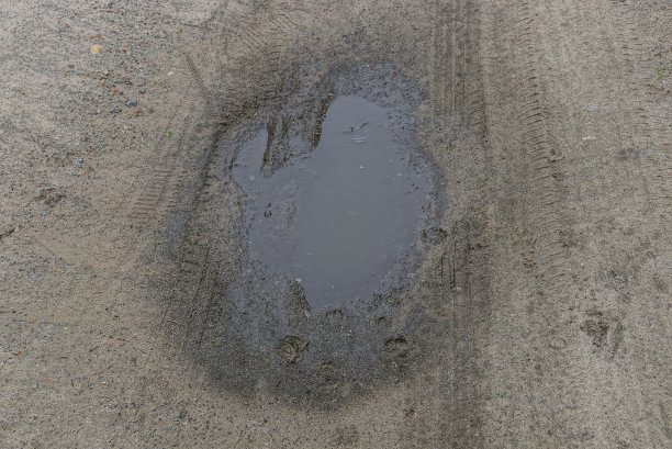 灰色泥泞的水坑和水在街上的沙路上图片下载