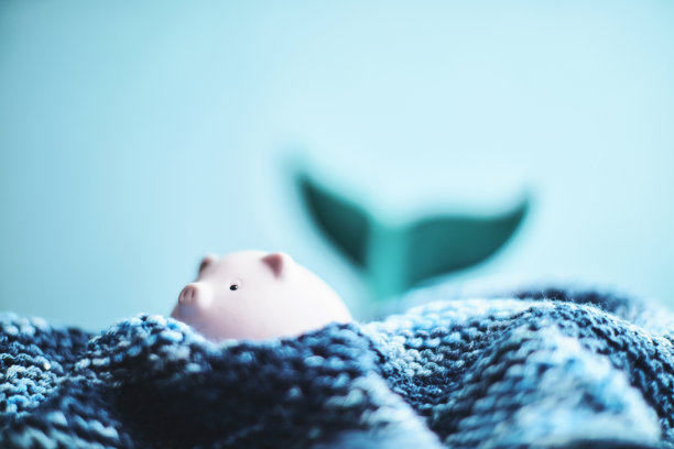 粉红色的小储蓄罐试图在手工制作的波浪中漂浮图片下载