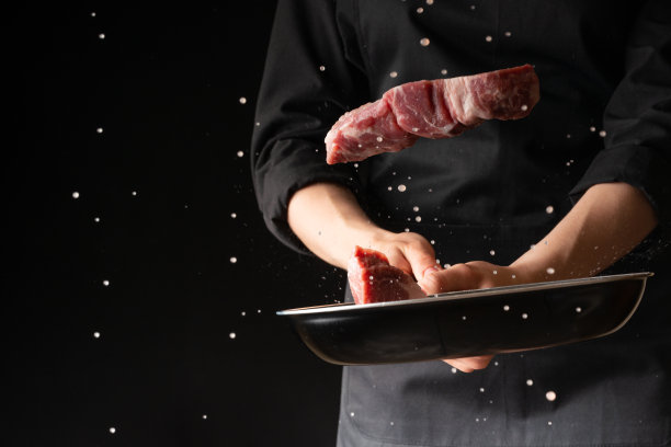厨师用肉、猪肉或牛肉烹制牛排，把新鲜的肉扔进平底锅里，在黑色的背景上，水平的照片，菜单，食谱，餐厅，美味的食物图片下载