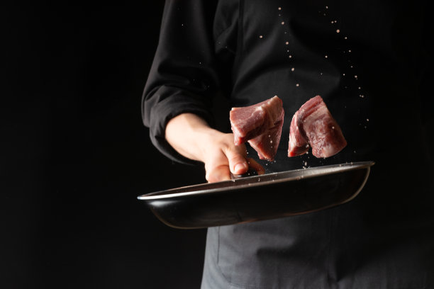 厨师用肉、猪肉或牛肉烹制牛排，把新鲜的肉扔进平底锅里，在黑色的背景上，水平的照片，菜单，食谱，餐厅，美味的食物图片下载