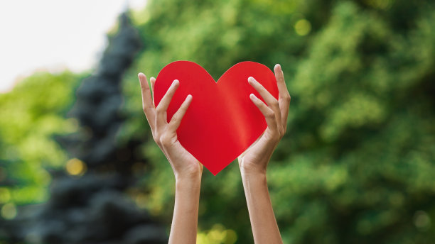 女人手牵着红心带着爱在公园里图片下载