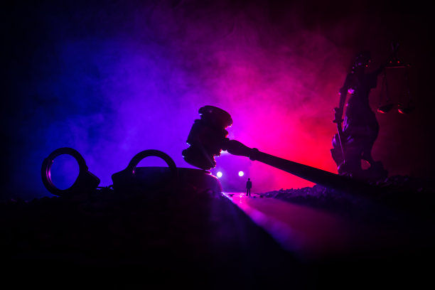 合法的法律概念。手铐的剪影与正义的雕像在背后与闪烁的红色和蓝色的警察灯在雾蒙蒙的背景。有选择性的重点图片下载