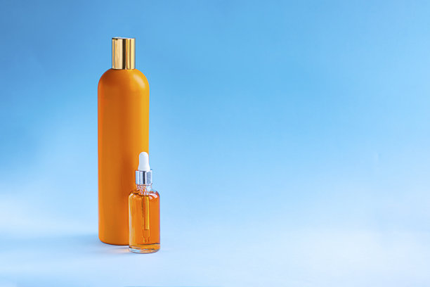 两个橘色瓶子，蓝色背景上有油。美容和化妆品的概念，瘦身和防晒，保健皮肤，护发，紫外线过滤。水平与复制空间图片下载