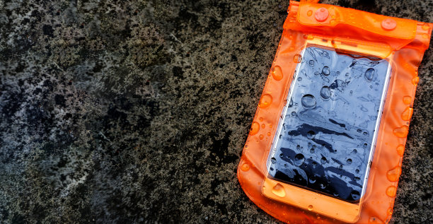 橙色防水手机外壳与水滴纹理背景。PVC拉链锁袋保护手机或重要物品的水。泰国泼水节的概念。图片下载